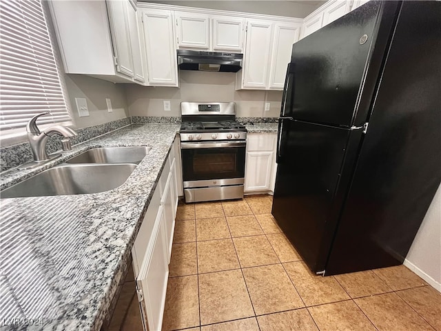 kitchen with sink, light tile patterned flooring, gas stove, black fridge, and white cabinetry