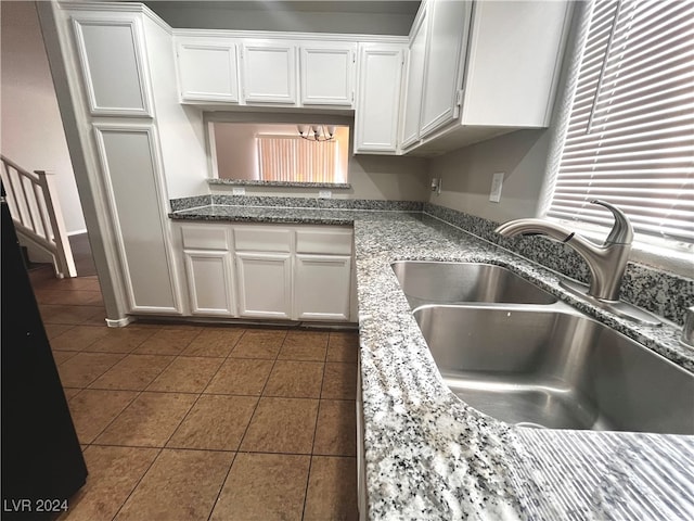 kitchen with stone counters, sink, dark tile patterned floors, and white cabinets