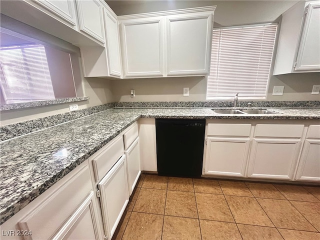 kitchen with light tile patterned floors, white cabinetry, dishwasher, dark stone countertops, and sink