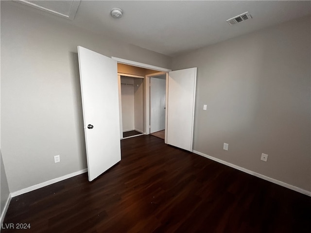 unfurnished bedroom with dark wood-type flooring and a closet