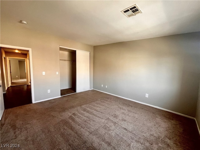 unfurnished bedroom featuring a closet and dark carpet