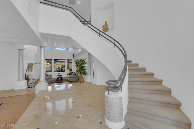 foyer with light hardwood / wood-style flooring, ornate columns, and a towering ceiling