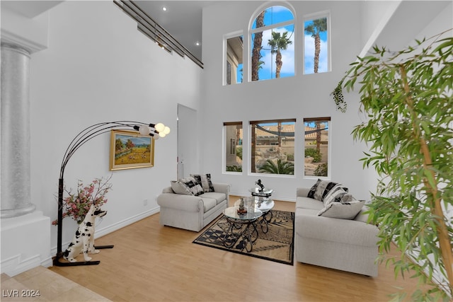 living room with decorative columns, light hardwood / wood-style flooring, and a high ceiling