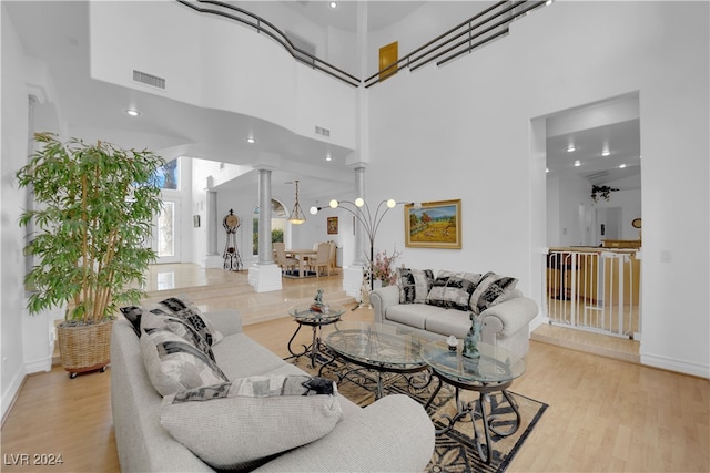 living room featuring a high ceiling, ornate columns, and light hardwood / wood-style floors