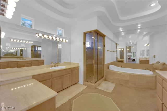 bathroom featuring vanity, independent shower and bath, and a tray ceiling