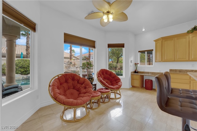 interior space featuring built in desk, ornate columns, and ceiling fan