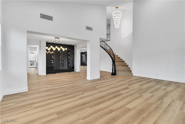 interior space featuring light hardwood / wood-style floors, a notable chandelier, and a high ceiling