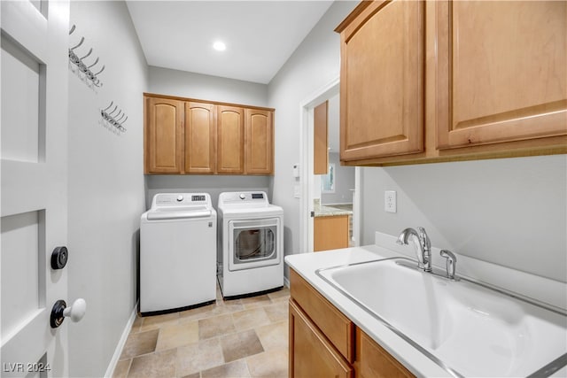 clothes washing area featuring cabinets, sink, and washing machine and dryer