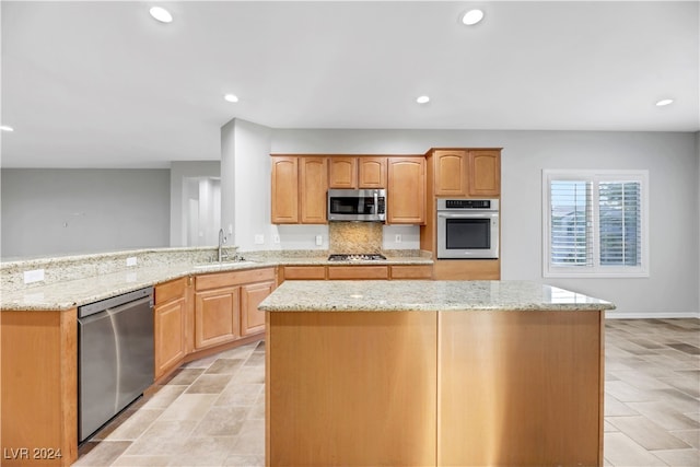 kitchen featuring light stone countertops, sink, appliances with stainless steel finishes, and kitchen peninsula