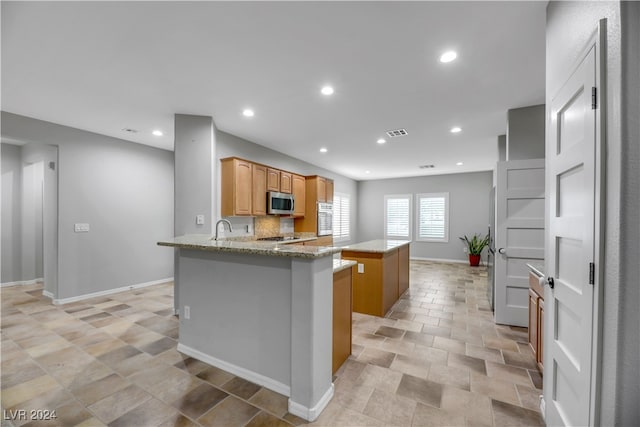 kitchen featuring sink, light stone countertops, and kitchen peninsula