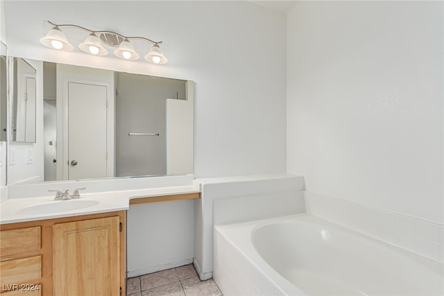 bathroom featuring vanity, tile patterned flooring, and tiled tub