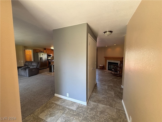 corridor featuring a textured ceiling and carpet