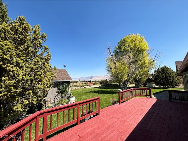 wooden deck with a mountain view and a lawn