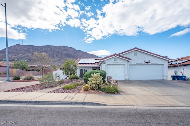 view of front of home with a garage, a mountain view, and solar panels