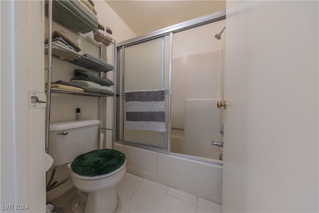 bathroom with tile patterned floors, shower / bath combination with glass door, and toilet