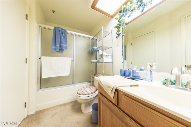 full bathroom with vanity, enclosed tub / shower combo, toilet, and a skylight