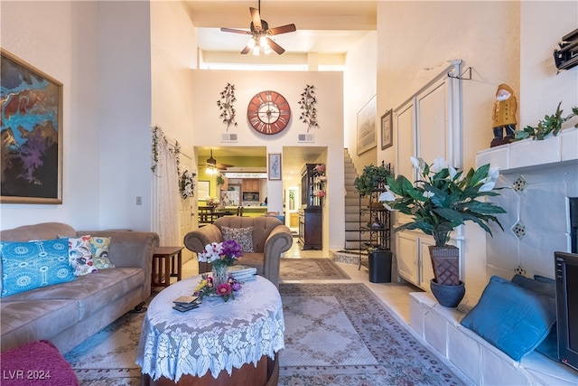 living room featuring ceiling fan, light tile patterned flooring, and a high ceiling