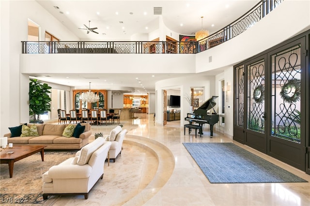 entryway with ceiling fan with notable chandelier and a high ceiling