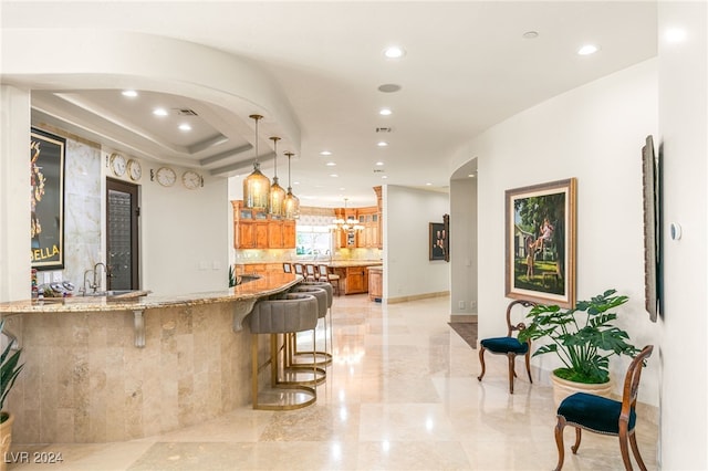 31 Eagles Landing Ln, Las Vegas, NV 89141 - kitchen featuring brown cabinetry, recessed lighting, light stone counters, a kitchen breakfast bar, and glass insert cabinets