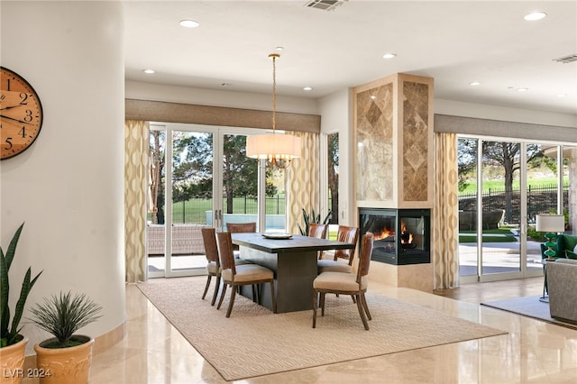 dining area with a large fireplace, a notable chandelier, and a healthy amount of sunlight