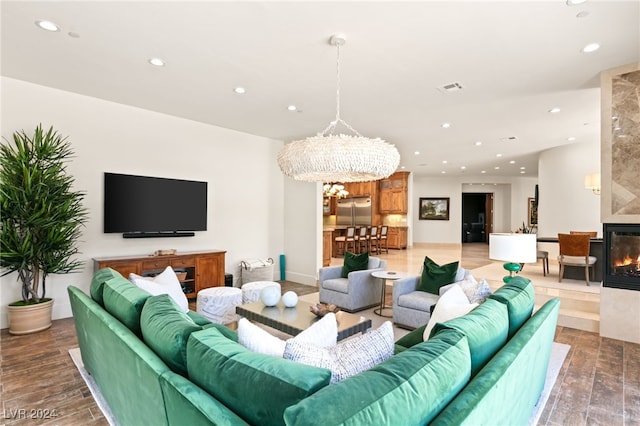 living room featuring an inviting chandelier, hardwood / wood-style flooring, and a large fireplace