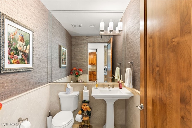 bathroom featuring tile walls, a chandelier, and toilet