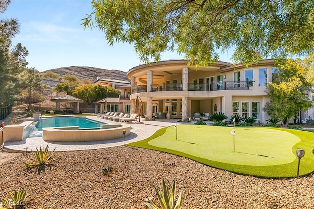 rear view of house featuring a mountain view, a pool with hot tub, a balcony, pool water feature, and a patio