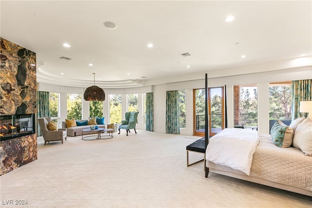 carpeted bedroom with a stone fireplace and access to exterior