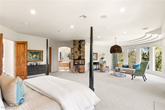 carpeted bedroom with connected bathroom and a fireplace