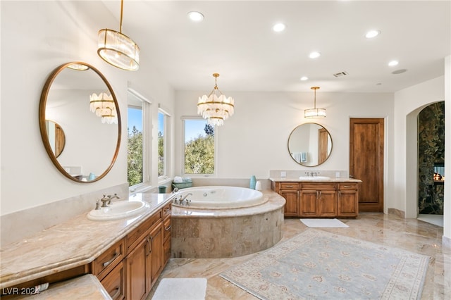 bathroom featuring an inviting chandelier, vanity, and tiled bath