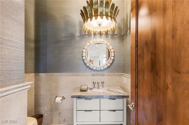 bathroom with vanity, toilet, and tile walls