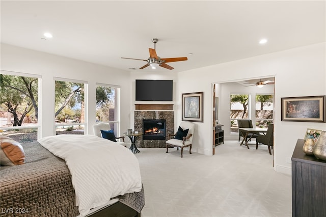 carpeted bedroom featuring a premium fireplace, multiple windows, and ceiling fan