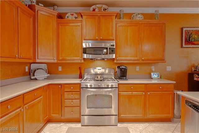 kitchen with appliances with stainless steel finishes, ornamental molding, and light tile patterned flooring