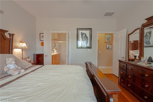 bedroom with ensuite bath and wood-type flooring