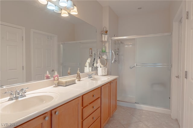 bathroom with a shower with door, vanity, and tile patterned flooring