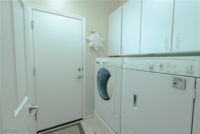 clothes washing area with cabinets, washing machine and dryer, and light tile patterned floors