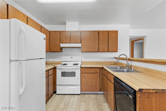 kitchen featuring under cabinet range hood, white appliances, a sink, light countertops, and brown cabinetry