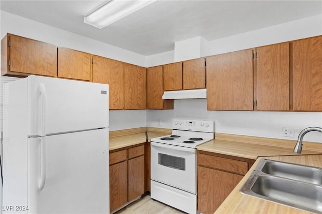 kitchen with light countertops, white appliances, a sink, and under cabinet range hood