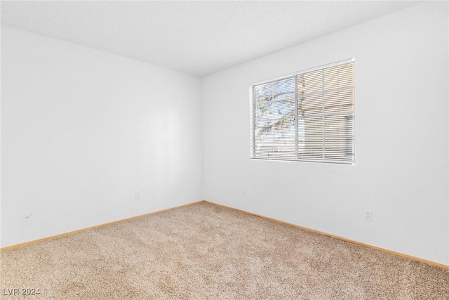 empty room featuring carpet and baseboards