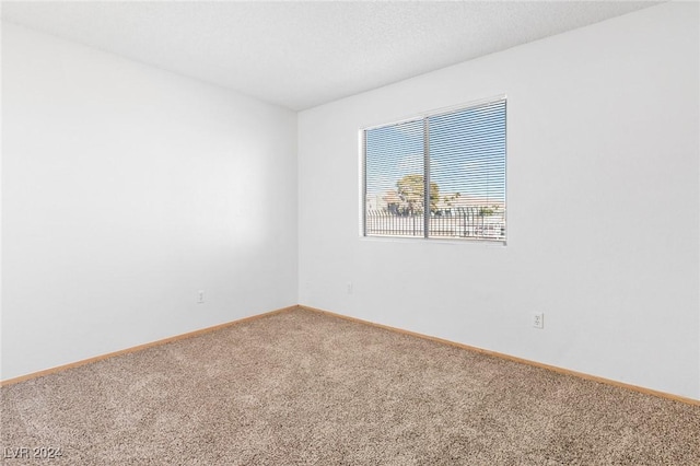 carpeted empty room with a textured ceiling and baseboards