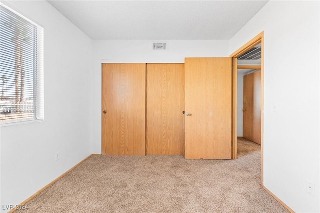 unfurnished bedroom with a closet, visible vents, and light colored carpet