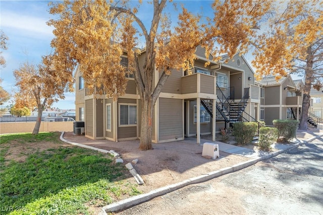 view of front facade with cooling unit, fence, a residential view, and stairs