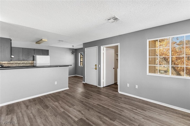 unfurnished living room featuring dark wood-style floors, visible vents, and a wealth of natural light