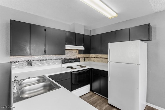 kitchen featuring light countertops, freestanding refrigerator, a sink, range with electric cooktop, and under cabinet range hood