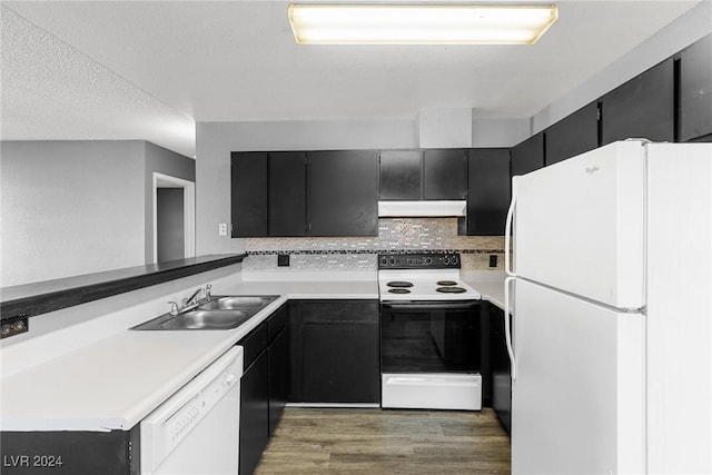 kitchen with dark cabinets, under cabinet range hood, white appliances, a sink, and light countertops