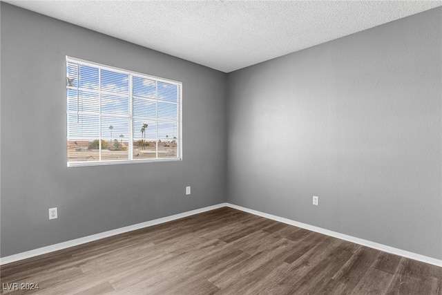 spare room featuring baseboards, dark wood finished floors, and a textured ceiling