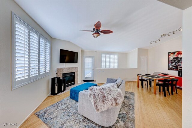 living room featuring ceiling fan, a fireplace, lofted ceiling, and light wood-type flooring