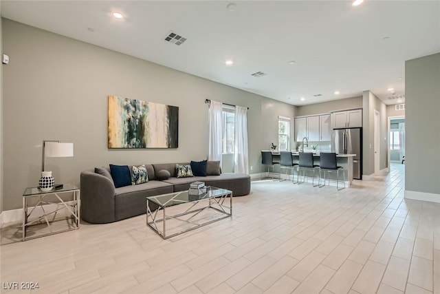 living room featuring light hardwood / wood-style flooring, a healthy amount of sunlight, and sink