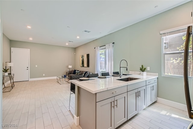 kitchen featuring sink, light stone countertops, gray cabinetry, and light hardwood / wood-style floors