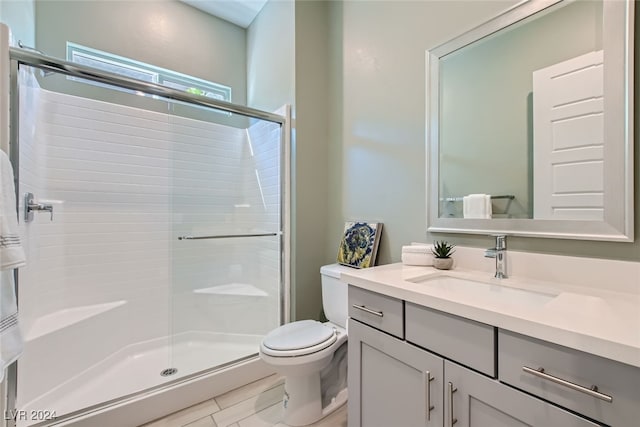 bathroom featuring vanity, toilet, tile patterned floors, and a shower with shower door